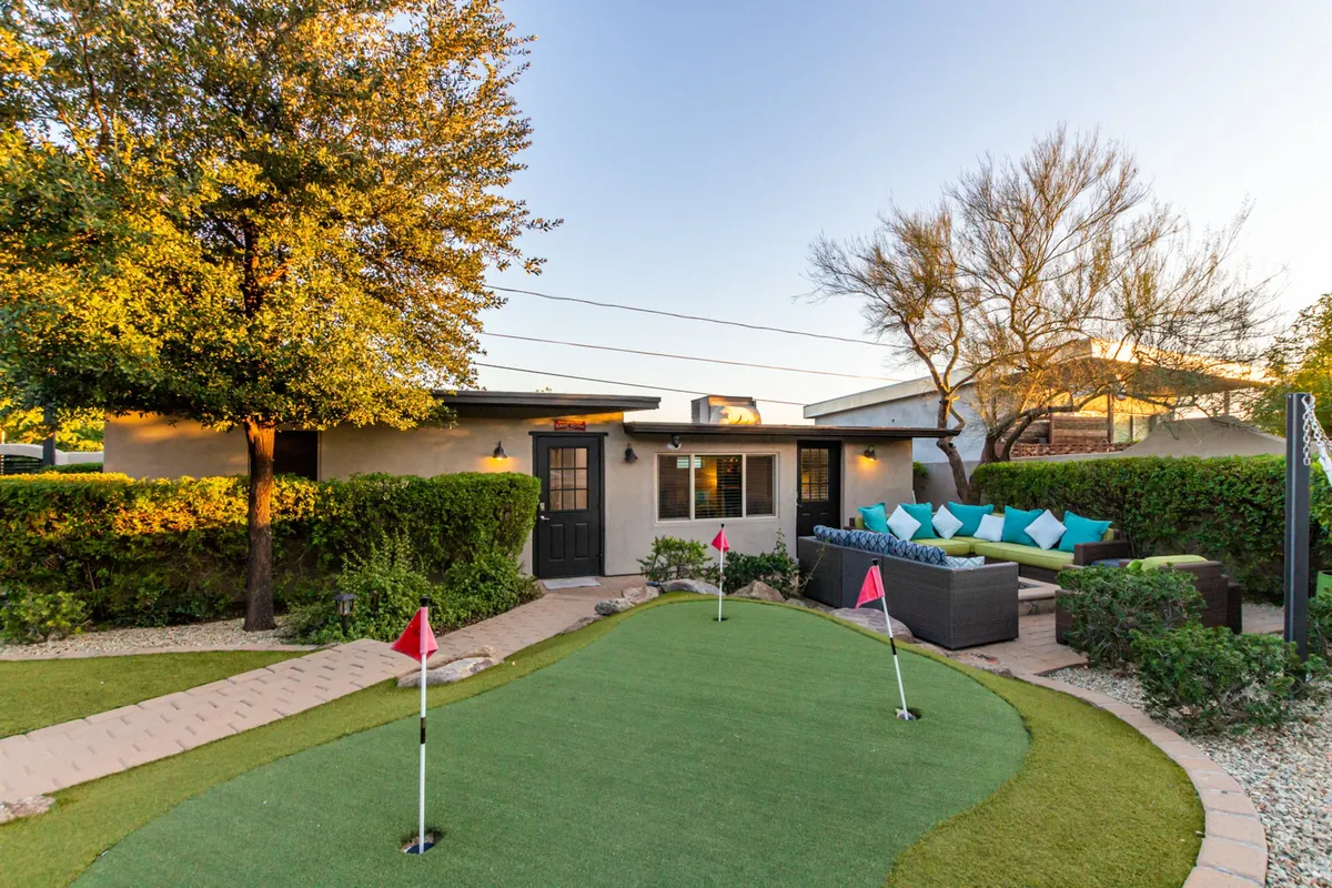 The image features a putting green and an inviting outdoor seating area, surrounded by neatly landscaped greenery. The setting encourages social interaction and informal golf practice, providing a relaxing space for guests to unwind or engage in friendly competition.