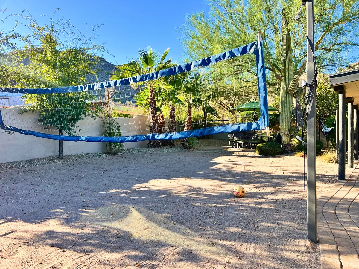 A sand volleyball court set among palm trees, with an adjacent outdoor seating area perfect for spectators or social gatherings. The sandy court invites playful competition, while the palm-fringed seating offers a relaxing spot to enjoy the action.